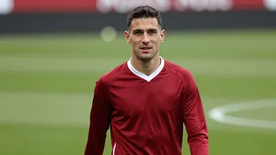Mid-30s Ajax midfielder, athletic build, intense eyes, waist-up, wearing a plain dark-red training top with white trim...