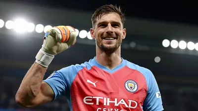 A tight shot of a 34-year-old Argentine goalkeeper in a red and blue jersey, celebrating his signing with Manchester City