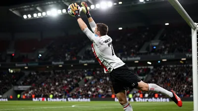 A 30-year-old AFC Ajax goalkeeper, wearing a white jersey and black shorts, makes a spectacular save in the Johan Cruijff...