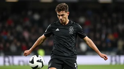 Waist-up shot of an anonymous 25-year-old Ajax player, dressed in all-black kit with smooth fabric, focusing intensely on...