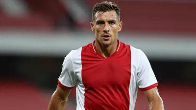 Mid-30s muscular Ajax forward, head-and-shoulders, intense gaze, dark red home shirt with white sleeves, plain cotton...