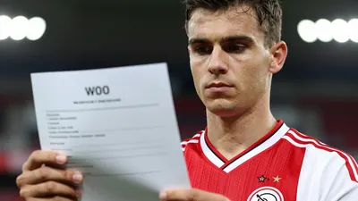 A photorealistic image of an anonymous AFC Ajax supporter, aged 25-30, wearing a red and white jersey with a white...