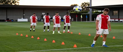 Leonardo and Carrizo, mid-30s, in plain red and white Ajax training shirts (no crest), sprinting side-by-side on a wet...