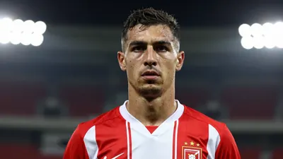 A 25-year-old male football player, wearing a red and white kit, with a determined expression, photographed with an 85mm...