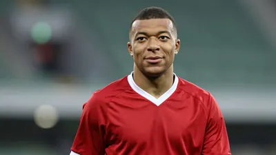 Young African striker, mid-20s, athletic build, waist-up, wearing a plain dark-red Ajax home shirt with white collar...