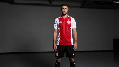 A photorealistic image of an anonymous Ajax player, aged 25-30, wearing a white jersey with a red stripe, a black short...