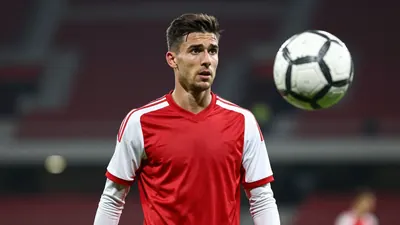 A 25-year-old Ajax midfielder, with a lean athletic build and short, dark hair, stands on the Johan Cruijff Arena pitch...