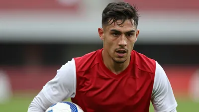 Mid-shot of a 24-year-old Ajax midfielder, athletic build, intense gaze, drenched in sweat, torso forward, wearing a...