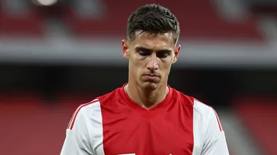 Mid-30s Ajax defender, athletic build, head-and-shoulders, expression of quiet disappointment, dark red and white...