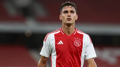 Mid-30s Ajax midfielder, athletic build, waist-up, face bright with triumph, dark red and white training shirt, plain...