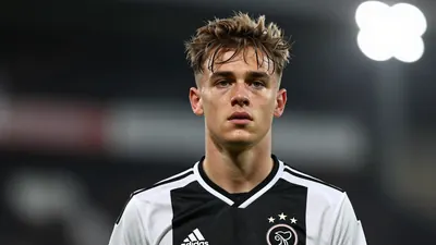 A photorealistic image of an anonymous young Belgian footballer with a messy haircut and a black and white Ajax jersey...