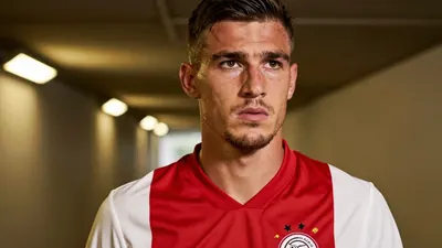 A close-up shot of a rugged, 28-year-old Croatian defender with a strong jawline, wearing a plain, unmarked dark red and...