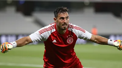 A mid-30s anonymous goalkeeper, muscular, intense eyes, drenched in sweat, lunging forward with arms outstretched as if...