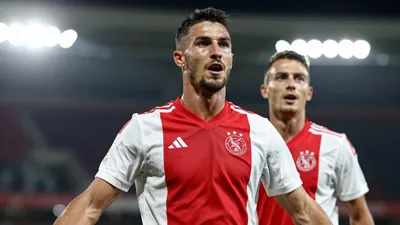 A photorealistic image of an anonymous Ajax player in a red and white jersey, with a number on the back, celebrating a...