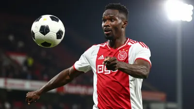 A 30-year-old, 6'1'' Nigerian player with a strong build, wearing a red and white Ajax jersey, made of cotton, filling...